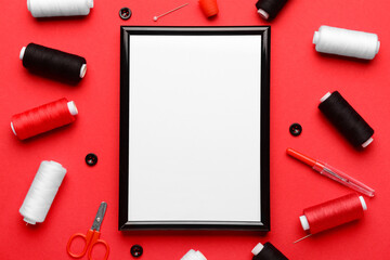 Blank picture frame with sewing supplies on red background