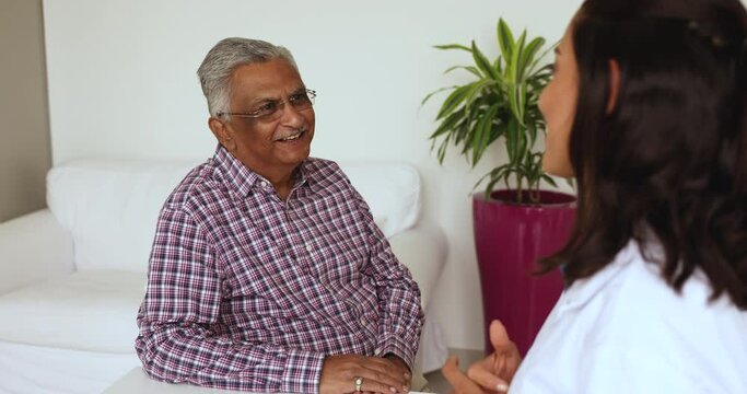 Communication of GP and older man. Aged senior patient talk to female general practitioner, share health complains, discuss treatment plan, having friendly conversation at visit in hospital. Eldercare