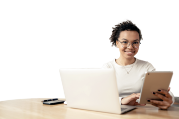 A young female student using a tablet and a laptop computer laughs while working online. An office employee, a young entrepreneur in the office.