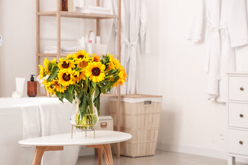 Interior of light bathroom with sunflowers in vase on table