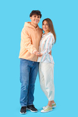 Young couple with key from house on blue background