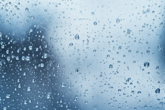 Close up image of an icy blue wet glass window, water drops, the rain on the window glass.
