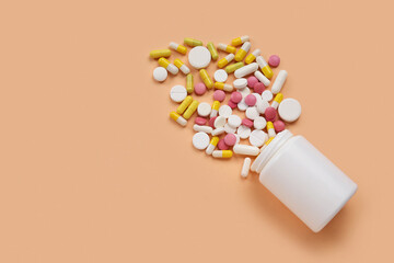 Jar with different scattered pills on orange background