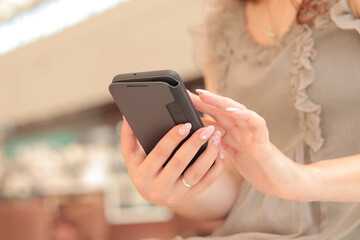 Gadget. Girl with a phone in her hands. Women's hands with a smartphone in a smart case, close-up. Use modern technologies, search on the internet, online purchases, online communication