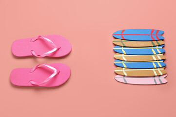 Different mini surfboards and flip-flops on pink background