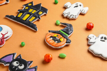 Composition with different tasty cookies and candies for Halloween celebration on beige background, closeup