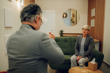 A senior female client is sitting on a couch in a doctor's office.