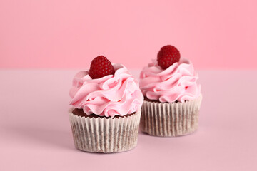 Tasty raspberry cupcakes on pink background