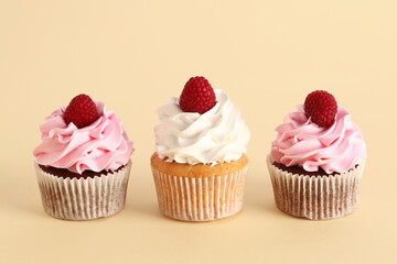Tasty raspberry cupcakes on beige background