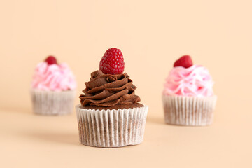 Tasty cupcakes with raspberries on beige background