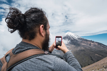 Mountaineer man taking photo with cell phone to a snowy mountain