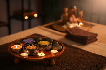 Spa composition with burning candles on table in dark salon, closeup