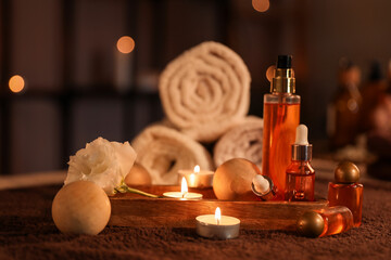 Spa composition with burning candles on table in dark salon, closeup