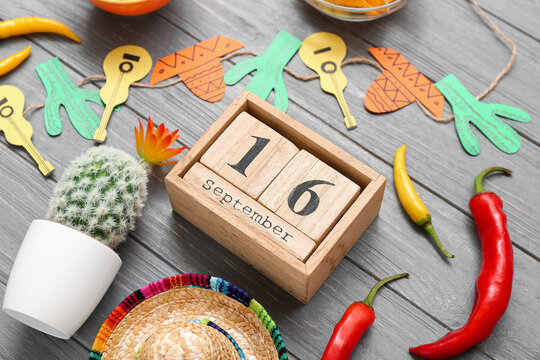 Cube calendar with date SEPTEMBER 16 and Mexican decor on grey wooden background. Mexico's Independence Day celebration