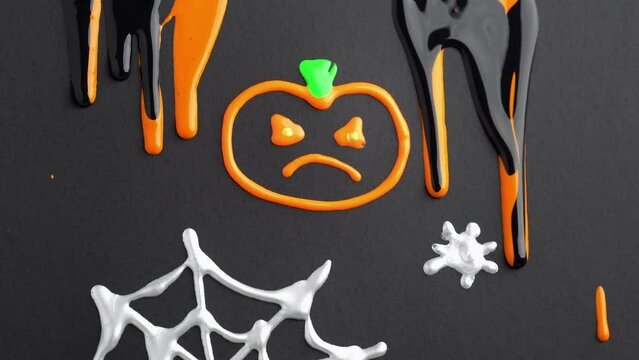 Liquid orange and black paint runs down the painted pumpkin on the black canvas. Halloween celebration concept. Cute Halloween background