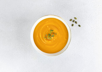 Pumpkin or carrot soup with a silky texture of pumpkin seeds on a white background. Top view.