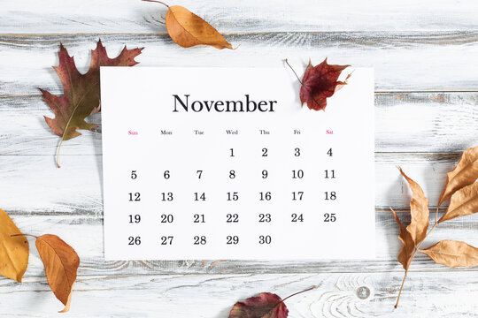 Autumn background with calendar for November month.  Flat lay, top view of fall leaves and calendar on light wooden background.