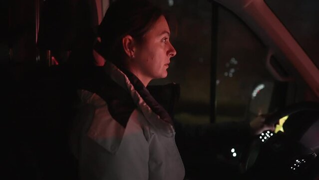 Woman driving moving truck at night. Female driver paying attention to highway road in evening journey
