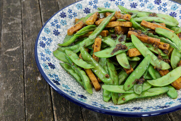 Sugar snap pea stir fry dish with tofu and Chinese five spice blend.
