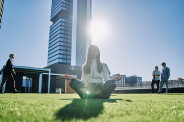 woman doing the yoga lotto pose with the sun shining in the background surrounded by office...