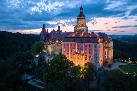 Evening aerial view of the illuminated Ksiaz Castle, Schloss Fürstenstein, a beautiful castle standing on a rock surrounded by forest in Lower Silesia Voivodeship, Poland. Largest castle in Sillt