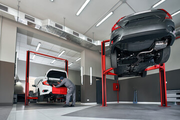 Professional car service. Comprehensive Car Care. Panoramic View of Dealership Service with Mechanic Repairing a Modern Sedan Car. Car shop.