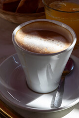White cup of coffee latte served in outdoor cafe in France