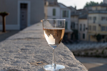 French rose dry wine from Provence in glass in sunny day with view on old streets of Arles town in...