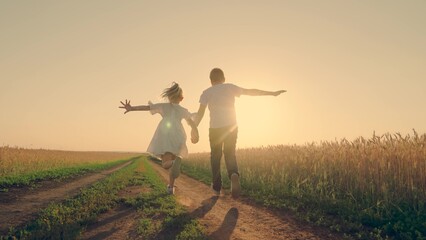 Children in together run through wheat field at sunset. Kids boy girl play fun run holding hands. Happy family. Carefree child in summer. Childhood dream concept. People, nature vacation. Farmer child