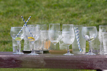 Empties- beer wine  and assorted other glasses left on table in beer garden on a hot sunny day after people have been partying and enjoying drinking outdoors . 