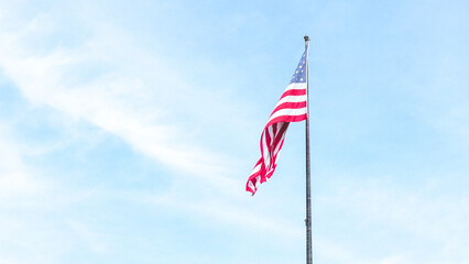 Beautiful American flag waving in the wind, with vibrant red white and blue colors against blue sky, with copy space.