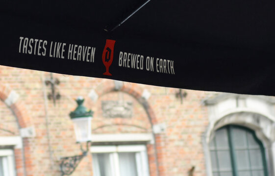 BRUGES, BELGIUM &ndash; SEPTEMBER 2, 2023: Advertisement for the strong blond Belgian Duvel beer on a beach umbrella with medieval building and streetlamp in the back. Selective focus