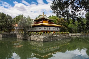 Fototapeta premium The beautiful Tsokyil Phodrong pavilion rests within Norbulingka, situated amidst the serene waters of a lake in Lhasa, Tibet.