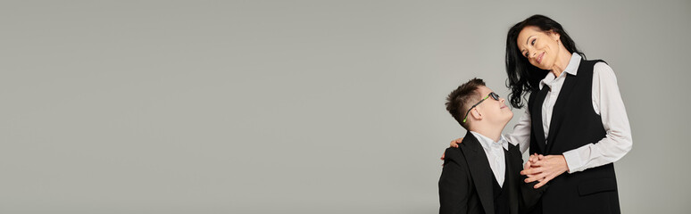 schoolboy with down syndrome holding hands with happy mother in formal wear, banner