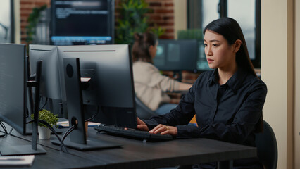 Asian software developer focused on writing code encounters unexpected compiling error sitting at...