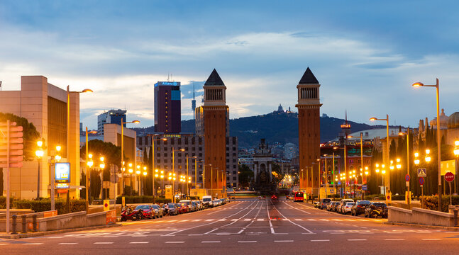 BARCELONA, SPAIN - JUNE 26, 2021: Picturesque cityscape in summer evening overlooking lighted avenue Avinguda de la Reina Maria Cristina with two Venetian Towers at junction with Placa dEspanya..