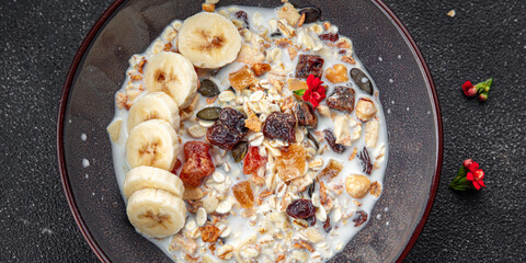fresh granola bowl milk, dried fruit and banana tasty breakfast meal food snack on the table copy space food background rustic top view 