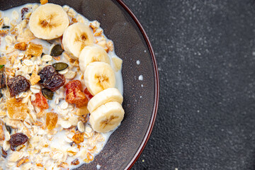 fresh granola bowl milk, dried fruit and banana tasty breakfast meal food snack on the table copy space food background rustic top view 