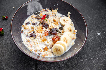 fresh granola bowl milk, dried fruit and banana tasty breakfast meal food snack on the table copy space food background rustic top view 