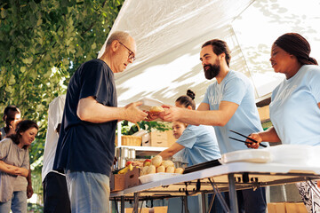 Multicultural team of humanitarian aid workers at food drive, sorting through donated food to ensure efficient distribution to less fortunate. Handing out of free meals to people in poverty.