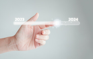 Obraz premium Hand touching on slide bar status to change from 2023 to 2024 for the countdown of Merry Christmas and Happy New Year by technology concept, Start a new business and new life.