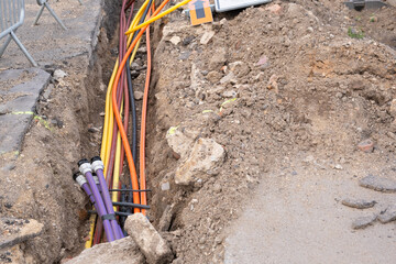 underground electric cable infrastructure communication installation. Construction site with various Cables protected in tubes. high-speed Internet Network cables are buried underground - obrazy, fototapety, plakaty