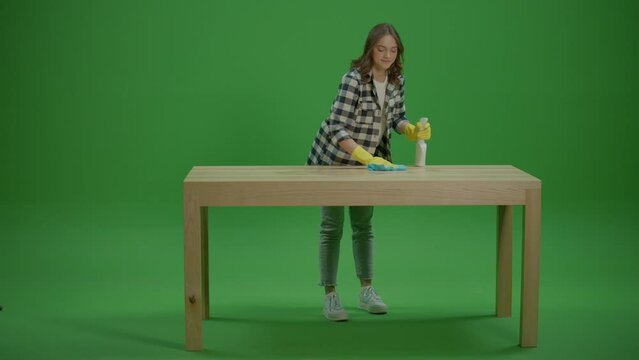 Green Screen.A Smiling Young Woman Housewife Cleaning the Table with a Spray Bottle and a Rab,Enjoying Cleaning. DIY Cleaning Solutions. Eco-friendly Cleaning.