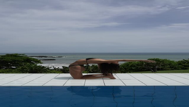 person relaxing on at the pool with ocean view in a tropical location practicing yoga camel pose backbends 