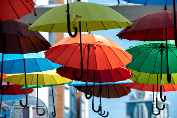 Fototapeta na wymiar many colorful umbrellas fly and hover on the city street