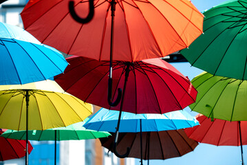 many colorful umbrellas fly and hover on the city street