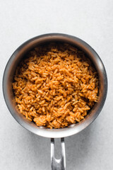 Jollof rice in a silver saucepan, homemade nigerian jollof rice in a pot, overhead view of authentic homemade west african jollof rice