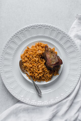 Jollof rice and fried chicken on a white plate, homemade nigerian jollof rice on a plate, overhead view of authentic homemade west african jollof rice