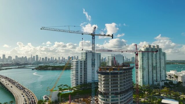 Tower lifting cranes at high residential apartment building construction site. Real estate development in Miami urban area