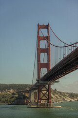San Francisco, CA, USA - July 13, 2023: Portrait, south alnding and tower of Golden Gate bridge under light blue evening sky. Presidio hills and ocean shoreline